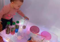 enfant avec boite lumineuse et matériel sensoriel